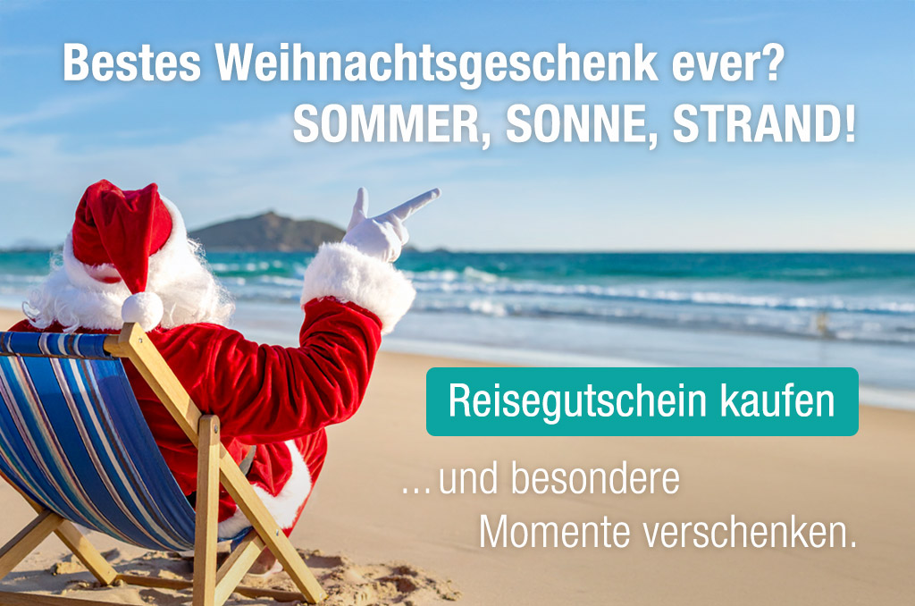 Weihnachtsmann in rotem Anzug sitzt im Liegestuhl am Sandstrand mit dem Meer im Hintergrund und deutet auf den Text "Reisegutschein kaufen" für Sommer, Sonne, Strand.